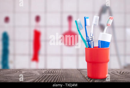Rote Container mit Zahnbürsten und Zahnpasta auf einem hölzernen Oberfläche vor dem Hintergrund der Badezimmer