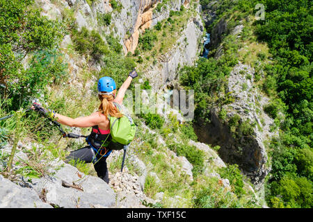 Junge weibliche Touristen das Tragen von Helm und Klettersteig Ausrüstung, Punkte ihre Hand in der Ferne, in Richtung Fluss Cikola, in Cikola Canyon, Kroatien, auf einem Hell Stockfoto