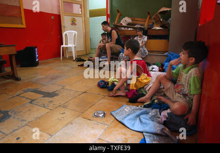 Flüchtlinge aus dem Südlibanon die Nachrichten im Fernsehen in einer Schule Unterricht in Beirut am 17. Juli 2006 Zehntausende meist libanesischen schiitischen Moslems sind auf der Flucht im Süden des Libanon und der Umzug in Schulen in anderen Teilen des Landes wie Israel seine Bombardements fort. Über hundert fünfzig Menschen im Libanon, meistens Zivilisten starben seit dem Konflikt am 12. Juli begann, nachdem die Hisbollah Guerilla zwei israelische Soldaten entführt und getötet, sieben andere. (UPI Foto/Norbert Schiller) Stockfoto