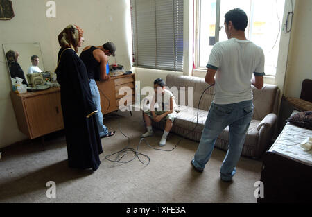 Die neu angekommenen Flüchtlinge aus dem Südlibanon schließen Sie Ihr Fernsehgerät an ein Kabel, in einer Schule, in Beirut am 17. Juli 2006. Zehntausende meist libanesischen schiitischen Moslems sind auf der Flucht im Süden des Libanon und der Umzug in Schulen in anderen Teilen des Landes wie Israel seine Bombardements fort. Über hundert fünfzig Menschen im Libanon, meistens Zivilisten starben seit dem Konflikt am 12. Juli begann, nachdem die Hisbollah Guerilla zwei israelische Soldaten entführt und getötet, sieben andere. (UPI Foto/Norbert Schiller) Stockfoto