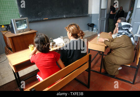 Flüchtlinge aus dem Südlibanon watch Berichterstattung über den Konflikt auf einem Fernseher in einer Schule Unterricht in Beirut am 17. Juli 2006 Zehntausende meist libanesischen schiitischen Moslems sind auf der Flucht im Süden des Libanon und der Umzug in Schulen in anderen Teilen des Landes wie Israel seine Bombardements fort. Über hundert fünfzig Menschen im Libanon, meistens Zivilisten starben seit dem Konflikt am 12. Juli begann, nachdem die Hisbollah Guerilla zwei israelische Soldaten entführt und getötet, sieben andere. (UPI Foto/Norbert Schiller) Stockfoto