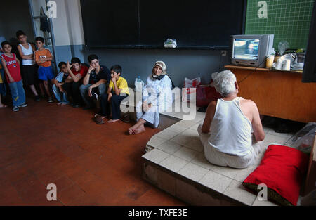 Flüchtlinge aus dem Südlibanon die Nachrichten im Fernsehen in einer Schule Unterricht in Beirut am 17. Juli 2006 Zehntausende meist libanesischen schiitischen Moslems sind auf der Flucht im Süden des Libanon und der Umzug in Schulen in anderen Teilen des Landes wie Israel seine Bombardements fort. Über hundert fünfzig Menschen im Libanon, meistens Zivilisten starben seit dem Konflikt am 12. Juli begann, nachdem die Hisbollah Guerilla zwei israelische Soldaten entführt und getötet, sieben andere. (UPI Foto/Norbert Schiller) Stockfoto