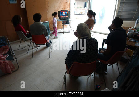 Flüchtlinge aus dem Südlibanon beobachten die Berichterstattung über den Konflikt im Fernsehen in einer Schule Unterricht in Beirut am 17. Juli 2006 Zehntausende meist libanesischen schiitischen Moslems sind auf der Flucht im Süden des Libanon und der Umzug in Schulen in anderen Teilen des Landes wie Israel seine Bombardements fort. Über hundert fünfzig Menschen im Libanon, meistens Zivilisten starben seit dem Konflikt am 12. Juli begann, nachdem die Hisbollah Guerilla zwei israelische Soldaten entführt und getötet, sieben andere. (UPI Foto/Norbert Schiller) Stockfoto