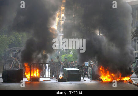 Die libanesische Armee steht, als die Demonstranten, verbündet mit der libanesischen Hisbollah - LED-politische Opposition, brennen Reifen, alte Autos und Straßen in der Hauptstadt Beirut am 7. Mai 2008. Eine allgemeine Arbeit Streik wurde für Gewerkschaften verlangt Einkommenserhoehungen genannt. Sporadische Gewehr - das Feuer war in der gesamten Hauptstadt gehört sowie Auseinandersetzungen zwischen rivalisierenden politischen Gruppen. Der Flughafen war auch geschlossen. (UPI Foto) Stockfoto