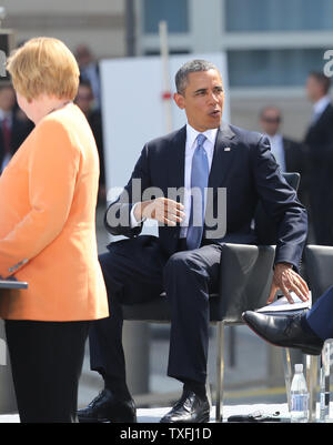 Us-Präsident Barack Obama (R) reagiert, nachdem es irrtümlich Denken war er an der Reihe zu sprechen, während die deutsche Bundeskanzlerin Angela Merkel die Masse am Brandenburger Tor in Berlin, die am 19. Juni 2013 Adressen. Obama ist in Berlin auf seinem ersten offiziellen Staatsbesuch in Deutschland und sprach an der historischen Stätte, wo 50 Jahre zuvor US-Präsident John F. Kennedy seinen berühmten "Ich bin ein Berliner (ich bin ein Berliner)' Adresse zugestellt. UPI/David Silpa Stockfoto