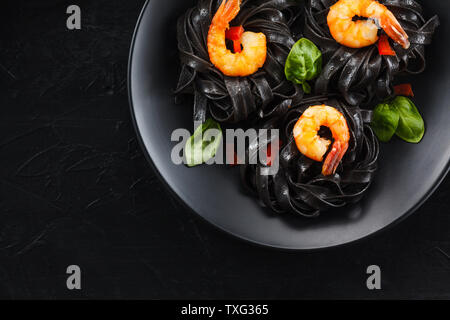 Squid inked Tagliatelle mit Garnelen auf schwarzen Hintergrund. Stockfoto