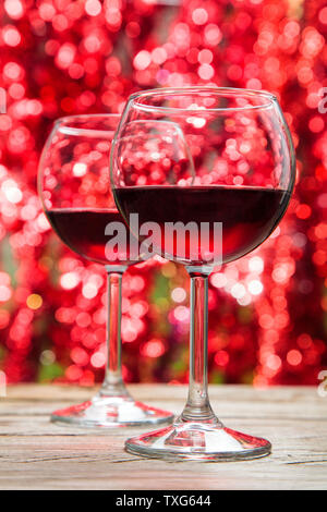Zwei Gläser Rotwein gegen defokussierten Holiday Lights Hintergrund. Stockfoto