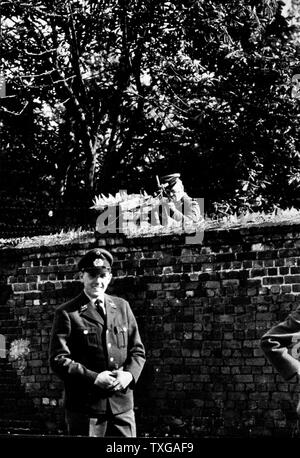 Berliner Mauer. West-Berliner in Uniform vor der Berliner Mauer, Soldat zeigenden Waffe über Mauer. Stockfoto