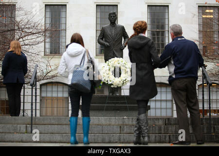 Menschen ihren Respekt an eine Statue von Präsident John F. Kennedy auf dem Rasen vor der Massachusetts State House in Boston am 22. November 2013 zu zahlen. Heute ist der 50. Jahrestag der Ermordung von JFK in Dallas. UPI/Matthew Healey Stockfoto