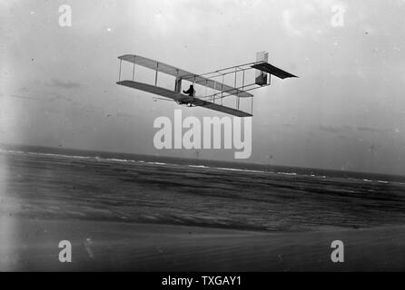 Linken hinteren Dreiviertelansicht der Gleitschirm im Flug in Kitty Hawk, North Carolina. Orville, begleitet von seinem Bruder Lorin, seinem Neffen Horace und seinem Freund Alexander Ogilvie, von England, kam zur Durchführung von gleiten Experimente mit einem Segelflugzeug Wright 1911 angetriebene Maschine ähnlich aber es mangelt an seinem Motor... Stockfoto