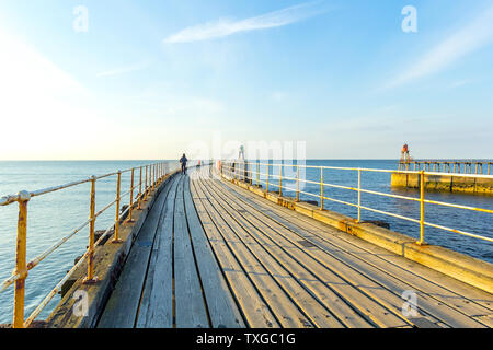 WHITBY, ENGLAND Touristen, Whitby Pier und den Leuchtturm. 12/05/2019 Stockfoto