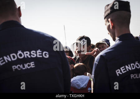 Flüchtlinge und Migranten warten auf Bussen in der Nähe von der Grenze mit Serbien in Roszke, Ungarn am 8. September 2015. Sie werden in eine Registrierung Camp, bevor sie ihre Reise in Richtung Deutschland übertragen werden. Foto von Achilleas Zavallis/UPI Stockfoto