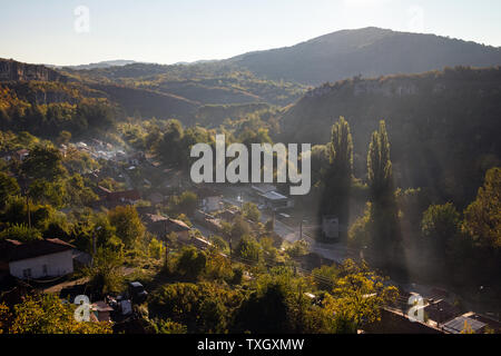 Luftbild des Schönen nebeligen Dorf zwischen Bergen in Lowetsch, Bulgarien. Misty sonnenaufgang Blick auf Stadtteil von Rock Mountain umgeben. Sun bea Stockfoto
