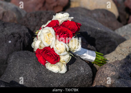 Rote und weiße Rose wedding bouquet Verlegung auf dem schwarzen Felsen. Stockfoto
