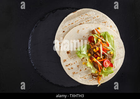 Burritos Wraps mit Hähnchen und Gemüse auf schwarzem Schiefer. Chicken burrito, mexikanisches Essen. Stockfoto