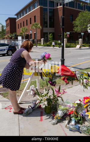 Ein Charleston resident fügt ein zu einem behelfsmäßigen Denkmal an der Polizei Barrikade in der Nähe, wo ein bewaffneter Bandit eröffneten das Feuer auf einem Gebetstreffen tötet neun Menschen an historischen Mutter Emanuel African Methodist Episcopal Church in Charleston, South Carolina am 17. Juni 2015. Der Verdächtige wurde nahm es am 18. Juni 2015 angekündigt wurde. Foto von Gillian Ellis/UPI Stockfoto