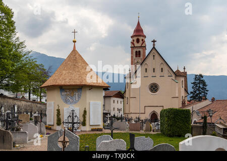 Panorama der Kirche, die Pfarrkirche St. Johannes der Taufer, mit Friedhof und Kapelle in der Gemeinde Dorf Tirol. Tirol, Südtirol, Italien Stockfoto