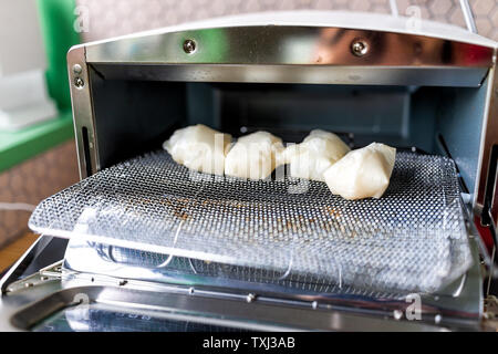 Mochi aufgeblasen bis Reis kuchen Plätze nach gebacken in kleinen Toaster Backofen in der traditionellen japanischen Weg am Rack Stockfoto