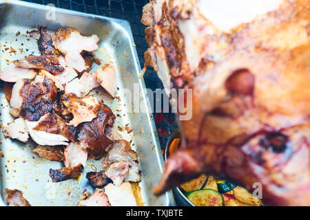 Chef Hände Schneiden ganze gegrillte Schweinefleisch für Steaks mit Messer. Vom Schwein gegrillte traditionelle Kohle und Feuer. Das kleine Schwein wird ganz auf einem offenen Feuer geröstet. P Stockfoto