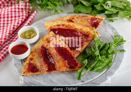 Geräucherten Rippchen Pizza mit Rucola und Parmesan auf Holz Tisch Hintergrund. Stockfoto