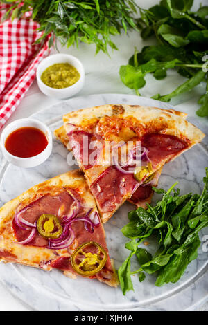 Geräucherten Rippchen Pizza mit Rucola und Parmesan auf Holz Tisch Hintergrund. Stockfoto