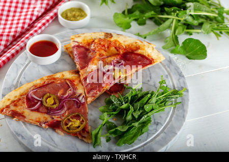 Geräucherten Rippchen Pizza mit Rucola und Parmesan auf Holz Tisch Hintergrund. Stockfoto