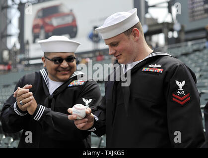 U.S. Navy Petty Officer Second Class Robert Dressler (R) und sein Freund Petty Officer Third Class Ralph Penass Blick an einem Baseball für die Ihnen von Detroit Tiger Krug Justin Verlander (35), bevor sie nach Hause Opener der Chicago White Sox gegen die Tiger an U.S. Cellular Field am 13. April 2012 in Chicago unterzeichnet. UPI/Brian Kersey Stockfoto