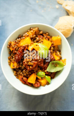 Kürbis mit Linsen, sonnengetrocknete Tomaten und Basilikum Stockfoto