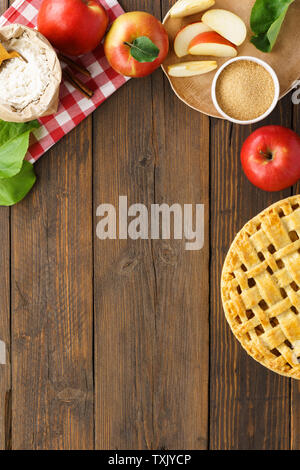 Gebackene Apfelkuchen und Zutaten zum Kochen - Zucker, Mehl, Äpfel, Zimt auf Holztisch. Saisonale Gebäck Hintergrund mit Kopie Raum für Rezept. Stockfoto