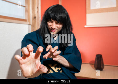 Traditionelle japanische Mann im Kimono Kostüm, und es ist schwarzes Haar tun Kampfkunst mit Händen von Alkoven Stockfoto