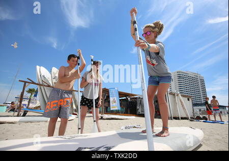 25. Juni 2019, Mecklenburg-Vorpommern, Warnemünde: Surf Lehrer Caro Schneider (r-l) gibt den Schülern Jessy Ritter und Jeremy Schult einen Kurs in Stand-up paddling. Die erste Rostock Strand Schule Tage am Strand von Warnemünde. Die wichtigsten Themen des Projekts Tage gehören "sicheres Baden' und 'Abfallvermeidung am Strand". Foto: Danny Gohlke/dpa Stockfoto