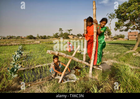 Mutter und Tochter Pumpen von Wasser mit einer Pumpe aktiviert zu Fuß auf einem abgelegenen Dorf in der Nähe von Lumbini, Nepal. Stockfoto