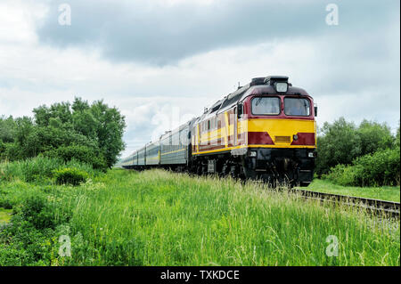 Personenzug fährt auf einer Spur außerhalb der Stadt. Stockfoto