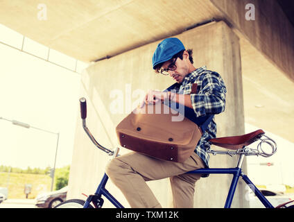 Hipster-Mann mit Fahrrad auf der Suche etwas in der Tasche Stockfoto
