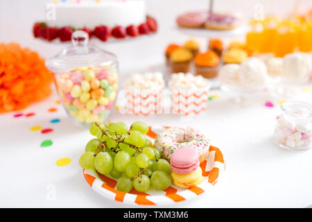 Trauben, Macarons und Krapfen auf Party Tabelle Stockfoto