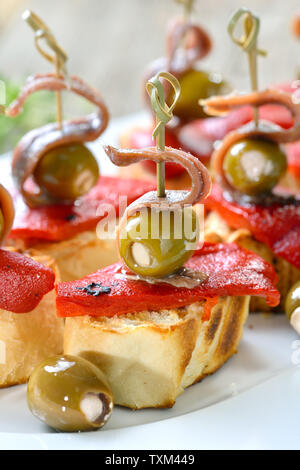 Spanische pinchos: Spieß snacks gegrilltes Brot mit gerösteten und eingelegte Paprika, gefüllte Oliven und und oben Anchovisfilets Stockfoto
