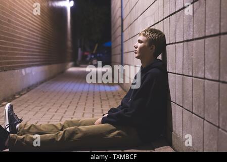 Traurig jugendlich sitzen in einer Gasse ganz allein in der Nacht. Stockfoto