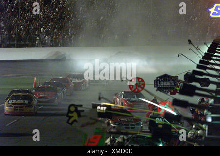 Scott Wimmer in der Katze Dodge führt den Satz durch den Rauch von Bobby Hamiltons brennenden Auto in Grube Straße Eingang während der 46. jährlichen NASCAR Nextel Cup Pepsi 400 in Daytona International Speedway in Daytona Beach, Florida, am 3. Juli 2004. (UPI Foto/Martin Fried) Stockfoto