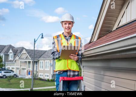 Junge männliche Architekt stand auf einer Leiter und in Sicherheit Gang gekleidet. Stockfoto