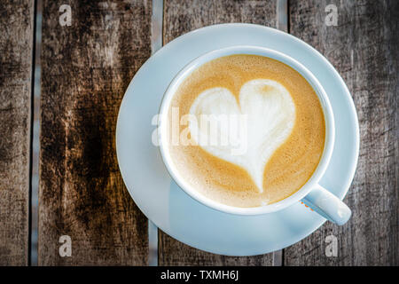 Eine Tasse Cappuccino mit einem gemalten Herzen steht auf einem Holz- strukturierte Tabelle. top View, close-up. Kostenlose leeren Raum. Stockfoto