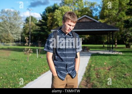 Angry student stehend auf einem Gehweg, der zu einem kleinen Pavillon führt. Stockfoto