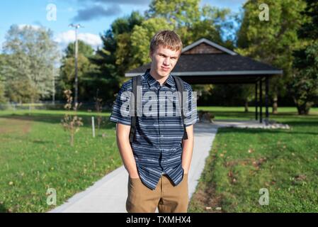 Angry student stehend auf einem Gehweg, der zu einem kleinen Pavillon führt. Stockfoto