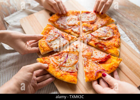 Nahaufnahme der Hand teilen Pizza auf hölzernen Tisch Stockfoto