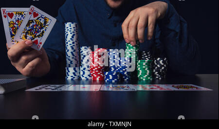 Der junge Mann poker Spieler Hände sichtbar Karten und Chips am Tisch. Spielen Turnier Sieger erfolg konzept über dunkle zurück Stockfoto