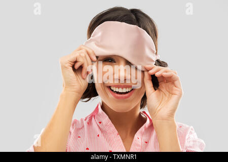 Glückliche junge Frau peeking unter Schlafbrille Stockfoto