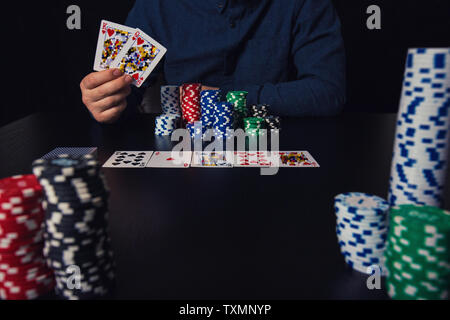 Der junge Mann poker Spieler Hände halten und zeigen die Karten wetten Chips am Tisch. Spielen Turnier Sieger Erfolg conce Stockfoto