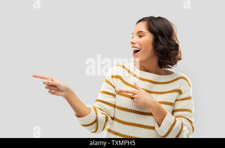 Glücklich lächelnde Frau zeigt die Finger etwas Stockfoto