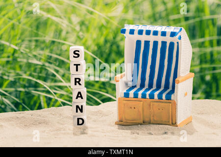 Würfel Form des deutschen Wort trand' ('Beach' in Englisch) Neben einem Strandkorb. Stockfoto