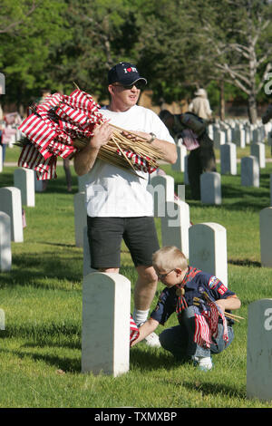 Glenn Brackett (oben) mit Sohn Jakob, 9, place amerikanische Flaggen auf grabstätten für Erinnerungstagesbefolgungen am Fort Logan National Cemetery in Denver, 27. Mai 2006. 87.000 Fahnen wurden von 300 freiwilligen Junge Pfadfinderinnen und Pfadfinder aus dem Denver Bereich platziert. Fort Logan National Friedhof wurde 1889 geschaffen und wurde nach General John A. Logan, allgemeine Ordnung Nr. 11, die Dekoration am 30. Mai, wurde später ein nationaler Feiertag "Memorial Day emittiert wurden benannt. (UPI Foto/Gary C. Caskey) Stockfoto