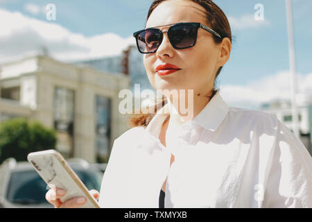 Close up Portrait von brunette elegante Frau business lady in Sonnenbrille mit Mobile an der Stadt. Stockfoto